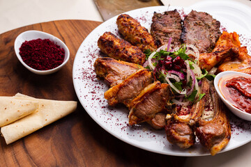 White plate with different types of meat prepared on the grill by special Turkish recipe. Delicious kebab plate with spices and lavash. Meat prepared on the barbeque with special sauce.