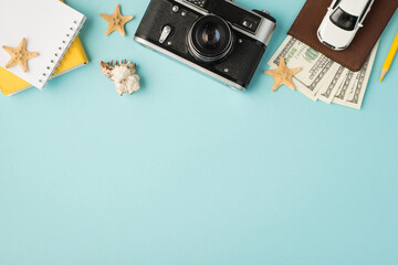 Top view photo of yellow notebooks camera pencil car model on passport cover with dollars seashell and starfishes on isolated pastel blue background with copyspace