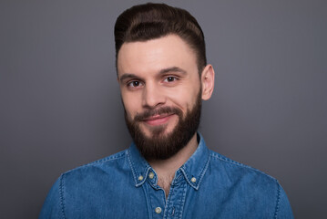 Close up portrait of confident serious bearded modern man while he looks on the camera