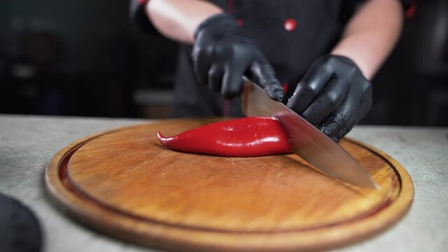 Close up shot of culinary master is cutting Red bell pepper to be prepared as a cooking ingredient in the restaurant's kitchen, Cut Red bell pepper on a white chopping board, 4K Footage.