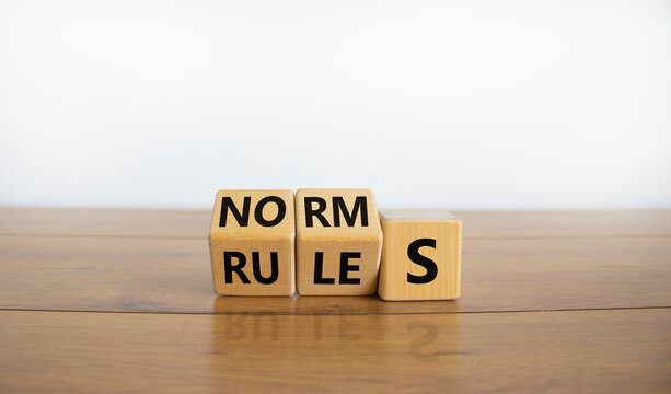 Rules or norms symbol. Turned cubes and changed the word 'norms' to 'rules'. Beautiful wooden table, white background, copy space. Business and rules or norms concept.