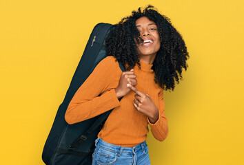 Young african american girl wearing guitar case smiling happy pointing with hand and finger