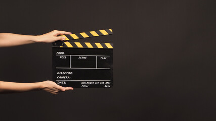 Hand is hold Black and yellow color clapper board or slate or movie clapperboard on black...