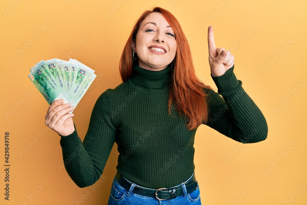 Canvas Prints beautiful redhead woman holding 5 singapore dollars banknotes smiling with an idea or question point