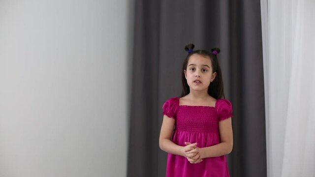 Focused girl stands at home reading script of play, preparing for casting for role in school theater. Lady small child repeats rules, learns verse, does homework in room in qurantine