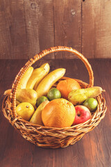 Basket and fresh fruits on wooden table and wood background,toned image.