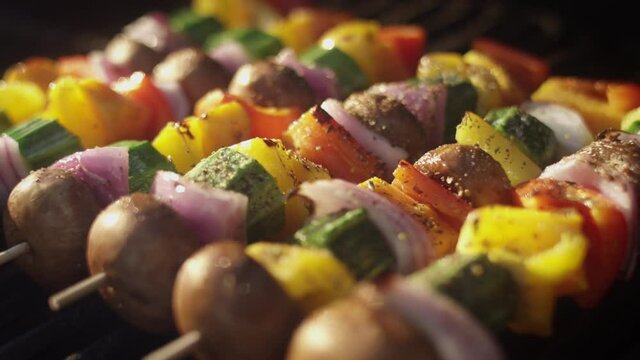 Panning shot across colorful vegetables smoking on the grill