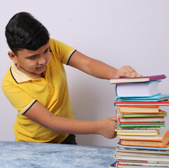 indian school boy or scholar kid with stack of books