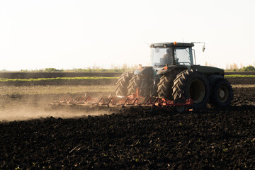 Fototapeta premium Tractor is preparing the land at dusk