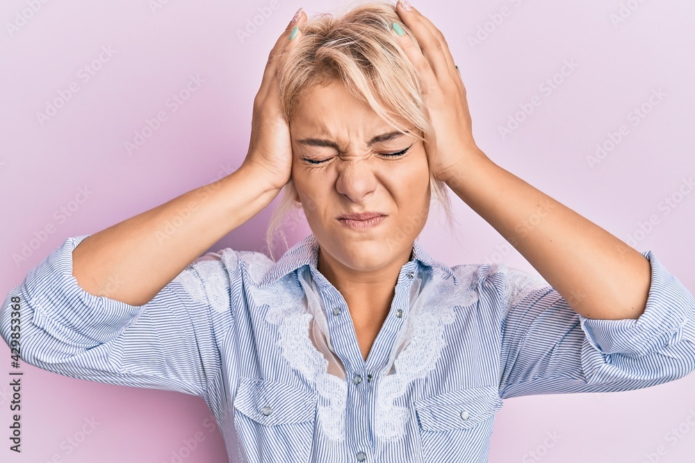 Poster Young blonde girl wearing casual clothes suffering from headache desperate and stressed because pain and migraine. hands on head.