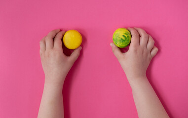 Children's hands hold macarons on a pink background. Flet lay.  © Visnjamarko