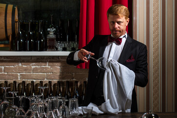 Restaurant staff cleaning. Waiter bartender rubbing glass. Barman at counter. Alcohol serving.