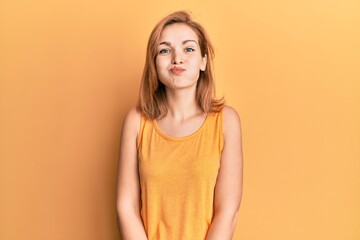 Obraz premium Young caucasian woman wearing casual style with sleeveless shirt puffing cheeks with funny face. mouth inflated with air, crazy expression.