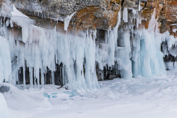 The rock on the frozen lake Baikal is covered with a thick layer of blue ice: many icicles and splashes.
