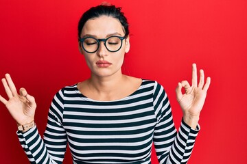 Young caucasian woman wearing casual clothes and glasses relax and smiling with eyes closed doing meditation gesture with fingers. yoga concept.