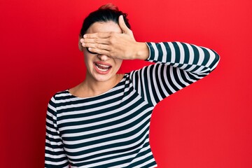 Young caucasian woman wearing casual clothes and glasses smiling and laughing with hand on face covering eyes for surprise. blind concept.