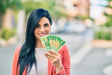 Young beautiful businesswoman smiling happy holding russian rubles banknotes at the city.