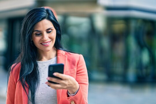 Young beautiful businesswoman smiling happy using smartphone at the city.
