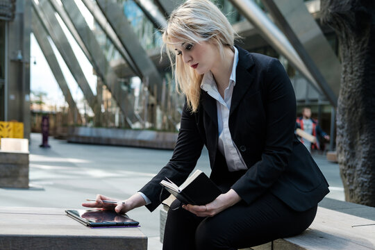 Business woman using a tablet with a notepad in the other hand.