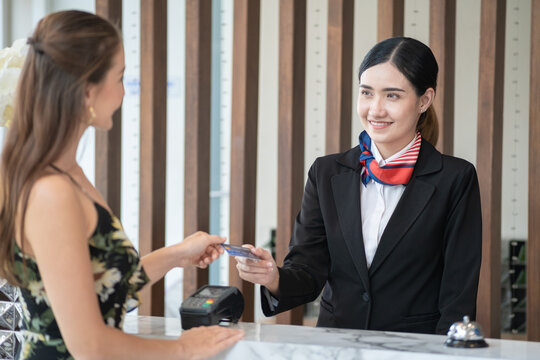 Asian Hotel reception receiving credit card from a woman customer for payment check-in hotel.