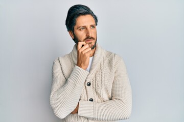 Young hispanic man wearing casual clothes thinking concentrated about doubt with finger on chin and looking up wondering