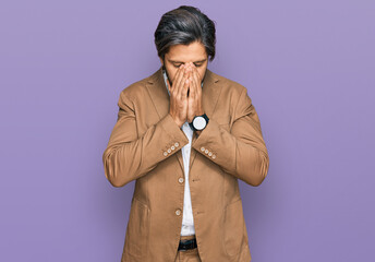 Young hispanic man wearing business clothes with sad expression covering face with hands while crying. depression concept.