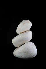 Fototapeta na wymiar 3 white stones stacked, isolated on black background, macro