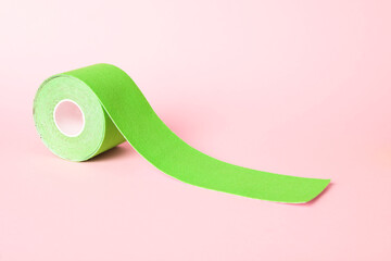 Green kinesio tape in roll on pink background