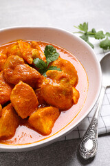 Bowl of delicious chicken curry on light grey table, closeup