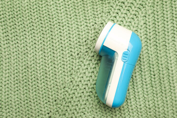 Modern fabric shaver for removing lint on green knitted cloth, top view