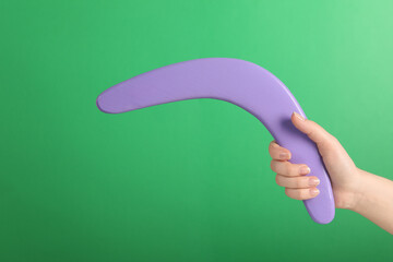 Woman holding boomerang on green background, closeup