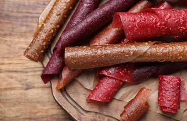 Delicious fruit leather rolls on wooden table, closeup