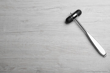 Reflex hammer on light wooden background, top view with space for text. Nervous system diagnostic