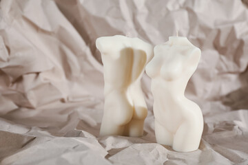 Fototapeta na wymiar Beautiful male and female body shaped candles on crumpled paper