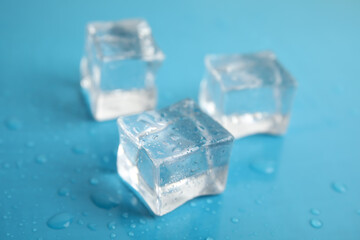 Ice cubes with water drops on light blue background, closeup