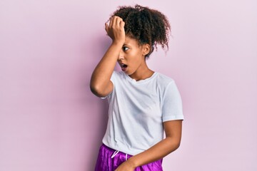 Beautiful african american woman with afro hair wearing sportswear surprised with hand on head for mistake, remember error. forgot, bad memory concept.