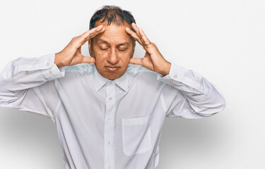 Middle age indian man wearing casual white shirt suffering from headache desperate and stressed because pain and migraine. hands on head.