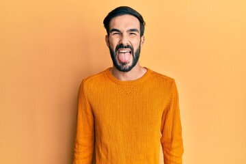 Young hispanic man wearing casual clothes sticking tongue out happy with funny expression. emotion concept.