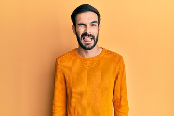Young hispanic man wearing casual clothes winking looking at the camera with sexy expression, cheerful and happy face.
