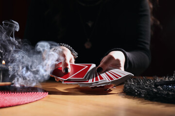 Soothsayer predicting future with cards at table indoors, closeup