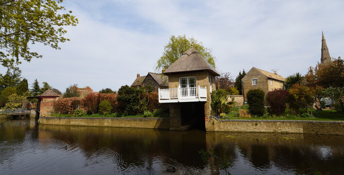 The river Ouse at Godmanchester  with old boathouse and church spire.
