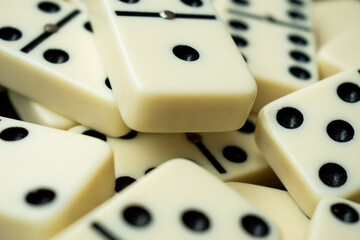 Close up of some white dominoes with  black points on a black table 