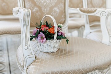 A small basket of flowers is lying on a chair in the ceremonial hall, wedding registration at a wedding. A wedding gift for the newlyweds. Decoration of roses. Close-up.