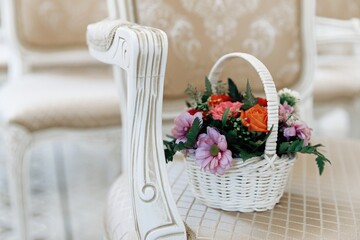A small basket of flowers is lying on a chair in the ceremonial hall, wedding registration at a wedding. A wedding gift for the newlyweds. Decoration of roses. Close-up.