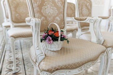 A small basket of flowers is lying on a chair in the ceremonial hall, wedding registration at a wedding. A wedding gift for the newlyweds. Decoration of roses. Close-up.