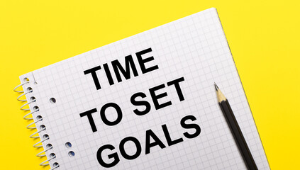 White notebook with inscription TIME TO SET GOALS written in black pencil on a bright yellow background.