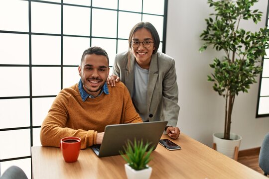 Two business workers smiling happy working sitting on desk at the office.