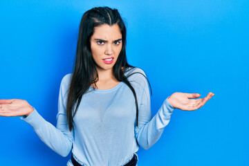 Fototapeta premium Young hispanic girl wearing casual clothes clueless and confused expression with arms and hands raised. doubt concept.