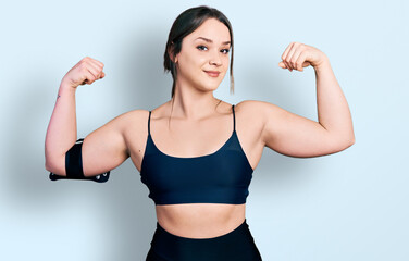 Young hispanic woman wearing sportswear showing arms muscles smiling proud. fitness concept.
