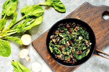 fried champignons with spinach in a pan.
top view. Copy space.